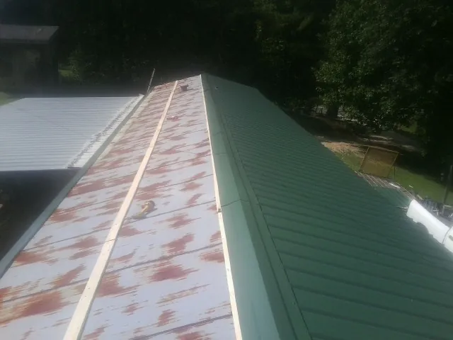 Old rusted panels beside newly installed green metal roofing — Wind Damage Roof Repair by Roofing Brothers in Meadowview