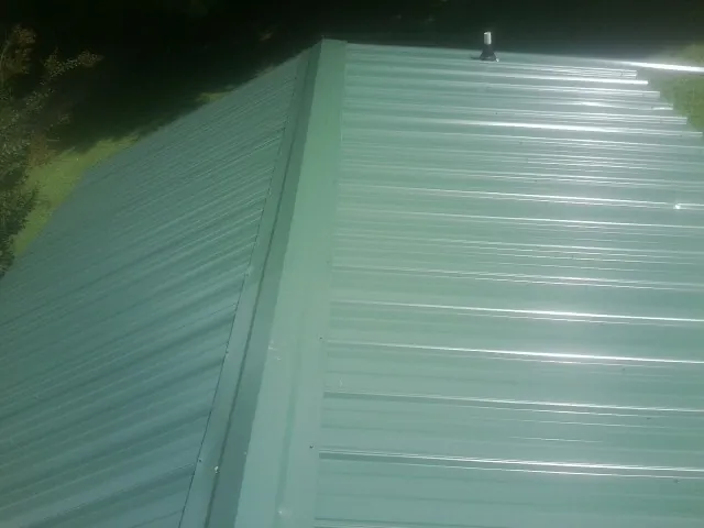 New green metal panels meeting at the ridge of a roof — Flat Roof Repair work by our crew in Meadowview