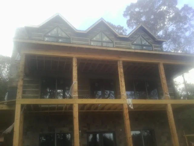 Dormers and porch framing on a large log home under construction — Roof Coating work by our crew in Meadowview